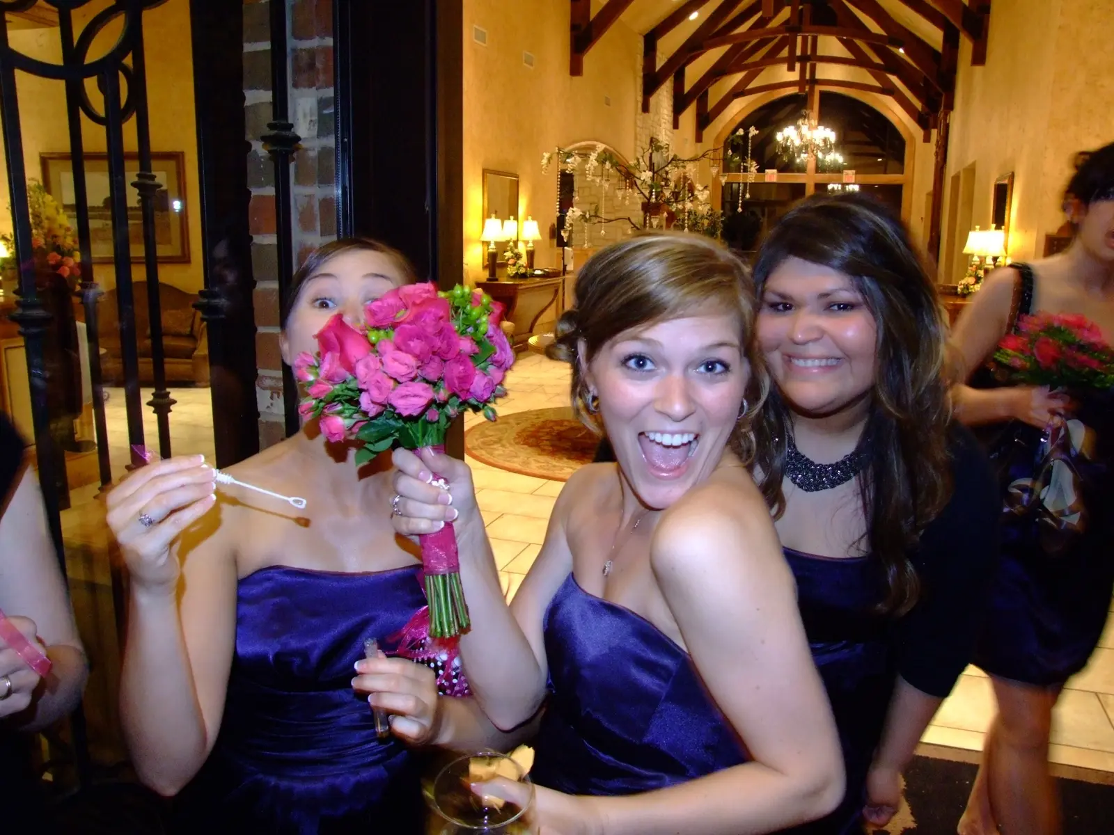 Bridesmaids laughing while one playfully hides behind a bouquet
