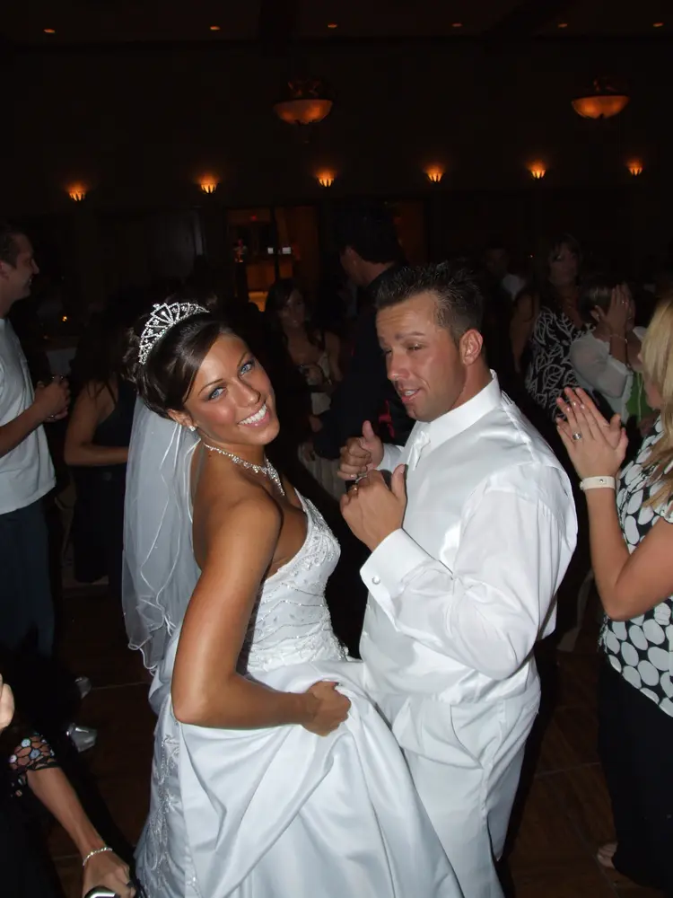 A bride and groom dancing among family and friends