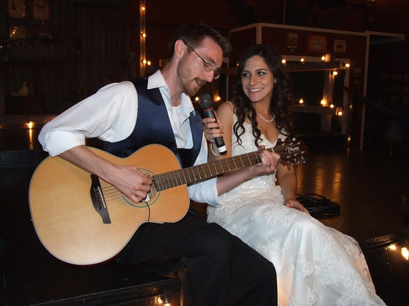 A groom playing guitar beside his bride during their reception